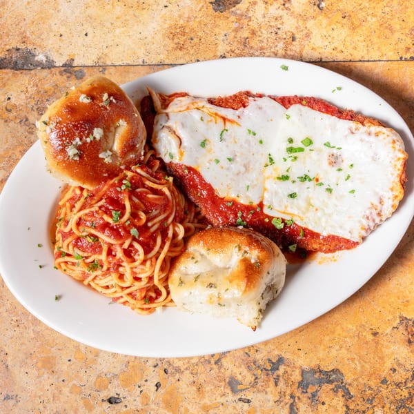 Chicken Parmesan with spaghetti in red sauce and two garlic knots on a white plate.